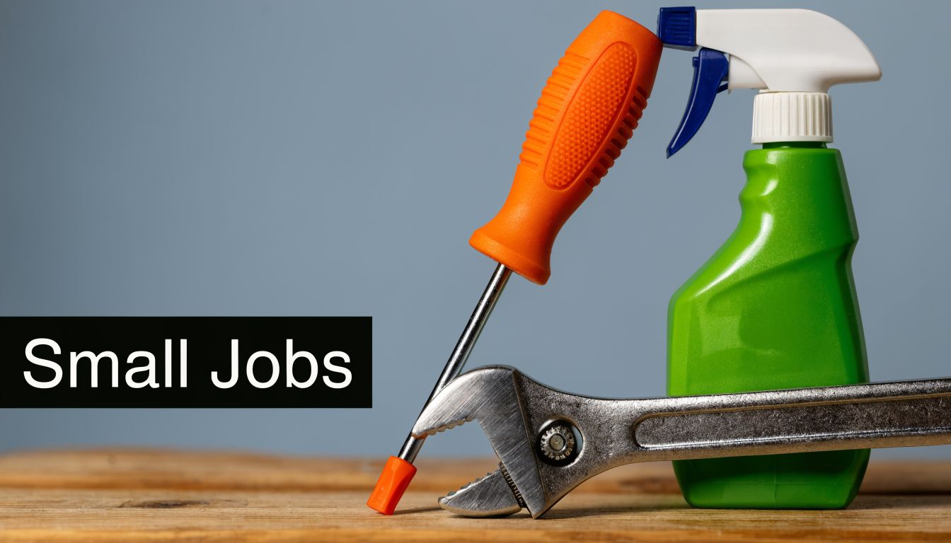 A screwdriver, an adjustable wrench, and a spray bottle on a wooden surface representing small household jobs.